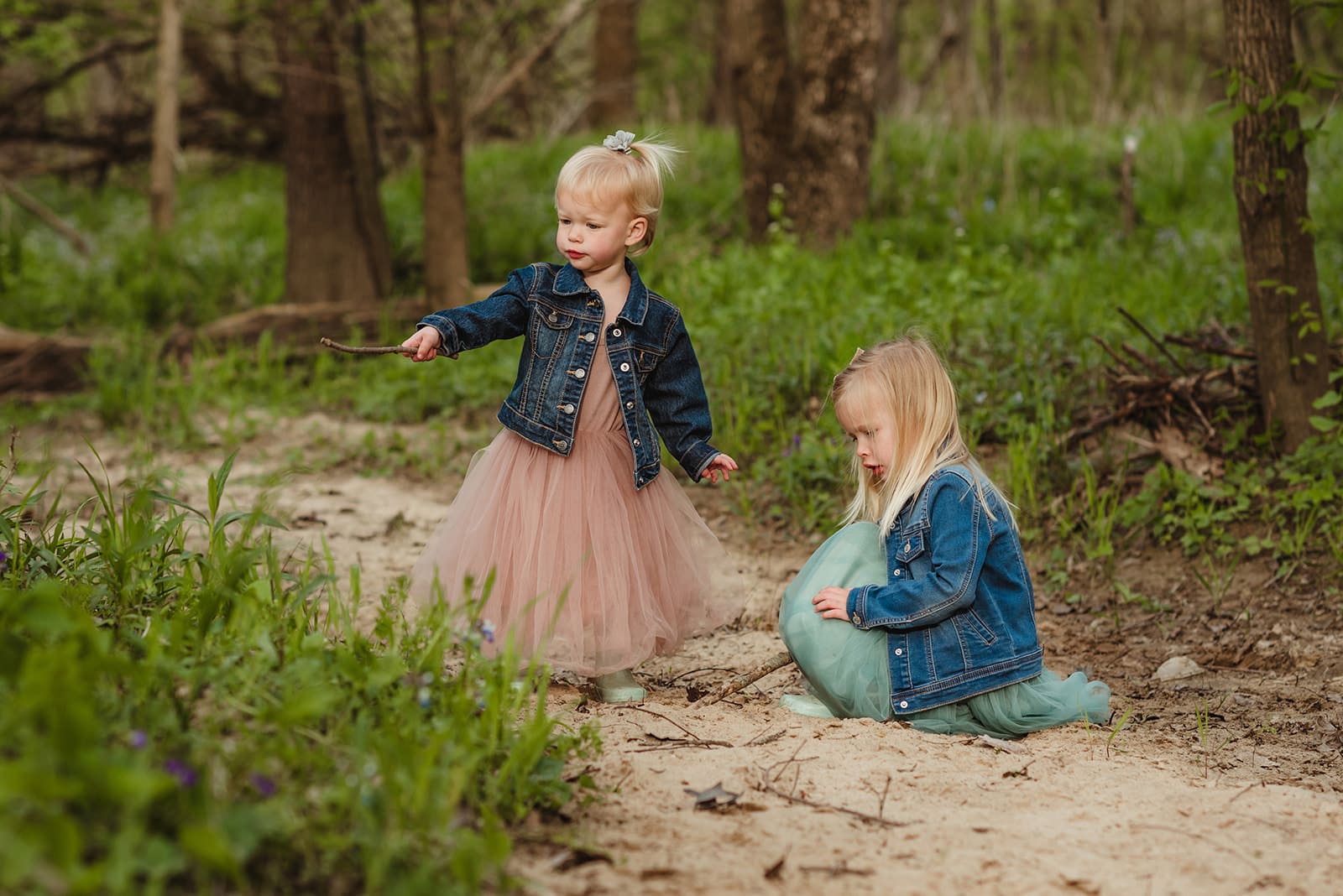 sisters in denim jackets and dresses playing on a dirt path
